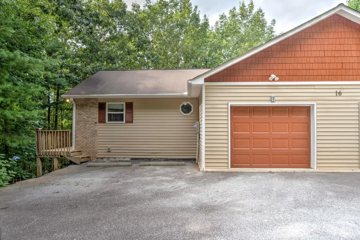 An exterior perspective featuring the garage door, entryway, and a wooden deck, with lush surroundings. The image exudes a cozy mood, showing the home’s approachable facade and the seamless transition from arrival to entry.
