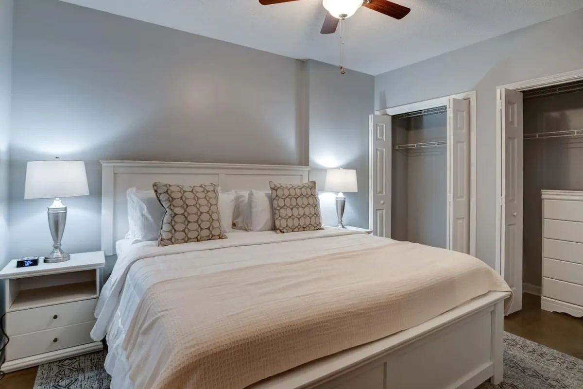 A serene and inviting king bedroom with a neatly made bed, elegant nightstands with lamps, and a spacious closet. The soft lighting and tranquil atmosphere suggest a restful haven for winding down after exploring Asheville's sights.