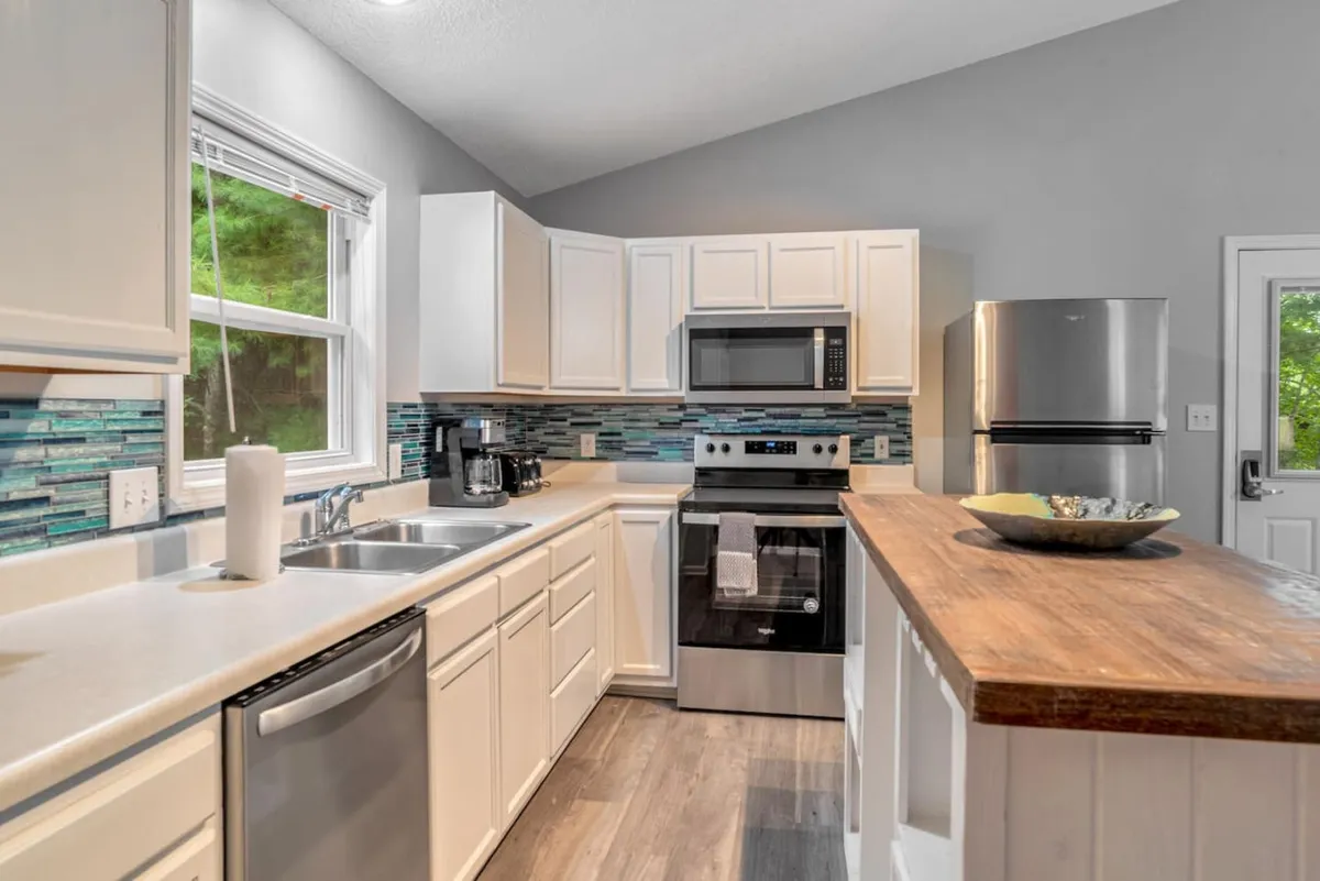 A stylish kitchen scene featuring a modern island, high-end appliances, and a colorful backsplash. The arrangement is warm and welcoming, perfectly suited for cooking, entertaining, or enjoying intimate family moments. The modern appliances and sleek countertops are clearly visible, emphasizing functionality and design.