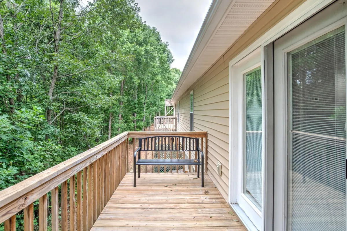 Another exterior perspective featuring a wooden deck with a bench, set against a backdrop of tall, leafy trees. The scene is peaceful, ideal for unwinding after a day of exploring Asheville's attractions or simply enjoying the breeze and wildlife.