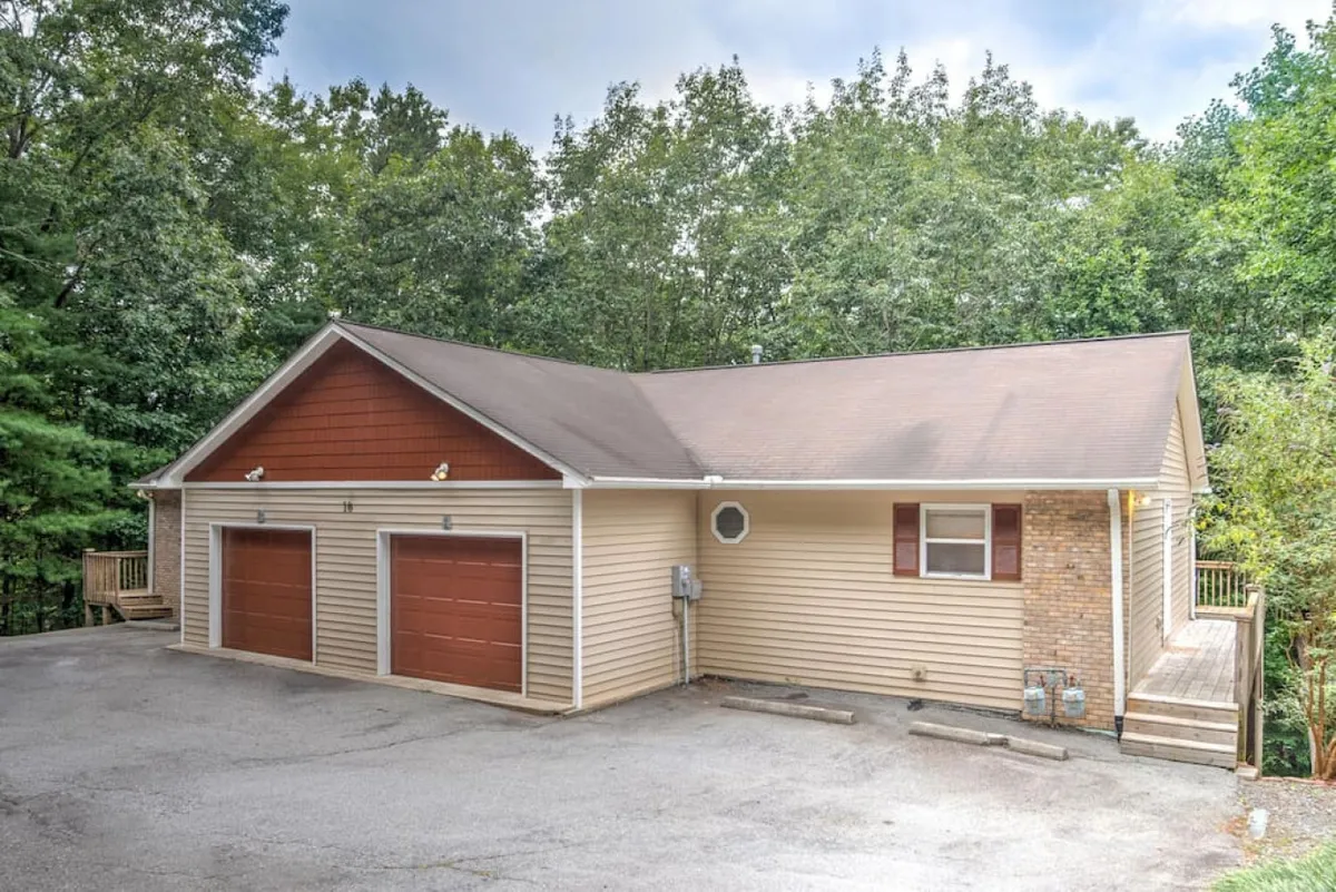 This exterior image spotlights two garage doors, a brick accent wall, and a wooden deck. The garage doors are prominent, making it immediately clear that dedicated parking is available for guests. The view also hints at surrounding tranquility and outdoor living, which aligns with the area’s inviting atmosphere.