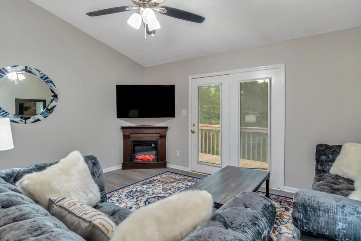 This image highlights a living room with a fireplace, comfortable sofa, coffee table, and double doors that suggest a spacious, open area. The space feels inviting and casual, with elements perfect for entertaining or relaxing.