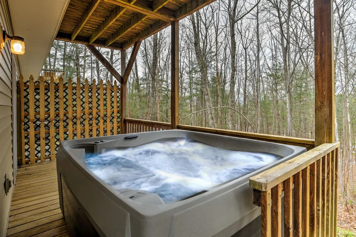 Featuring a hot tub on a wooden deck, framed by lush trees, this scene highlights a relaxing outdoor amenity. The environment suggests both social opportunities and solitary relaxation, with the added comfort of nature all around. The presence of the hot tub offers a touch of luxury for unwinding after time spent exploring the outdoors with a pet.